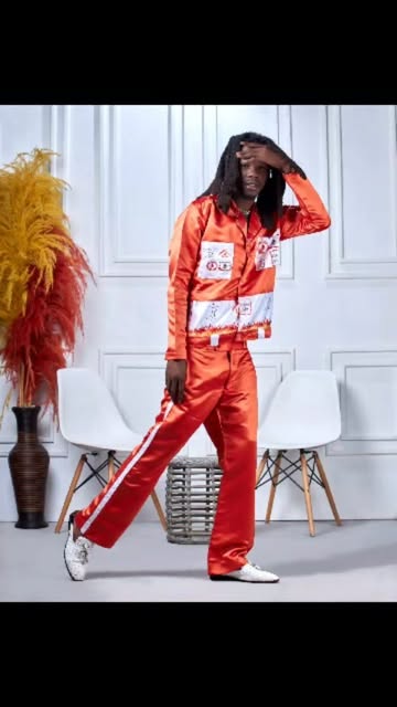 Man in an orange satin patch set posing in a white studio